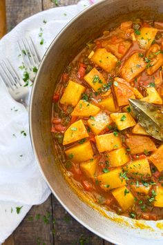 a large pot filled with stew on top of a wooden table next to a spoon