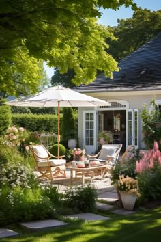 an outdoor patio with chairs, tables and umbrellas in the grass next to a house