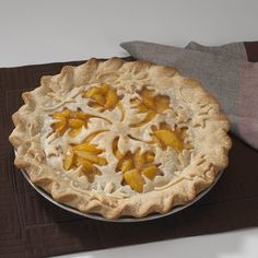 a pie sitting on top of a wooden table next to a brown cloth and pillow