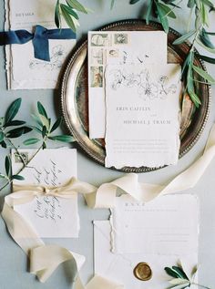 the wedding stationery is laid out on a silver platter and tied with ribbon