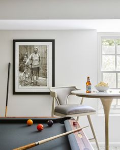 a pool table with two chairs and a framed photograph on the wall next to it