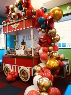 a red and white truck with balloons on it's side in front of a window