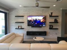 a living room filled with furniture and a flat screen tv mounted on the wall over a fireplace