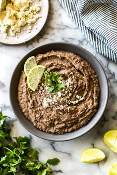 a bowl filled with hummus and garnished with cilantro, parsley and lime