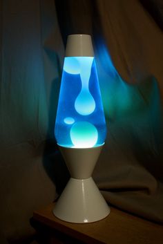 a blue and white vase sitting on top of a wooden table next to a wall