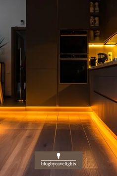 a kitchen with wooden floors and yellow lights on the walls, along with an oven