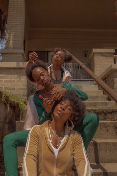 three women are sitting on the steps and one woman is touching her face with her hand