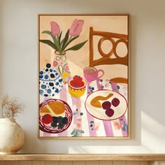 a painting hanging on the wall above a table with food and flowers in vases