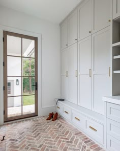 an empty room with white cabinets and brick flooring