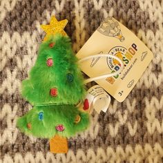 a small green christmas tree sitting on top of a carpet next to a package of toothpaste