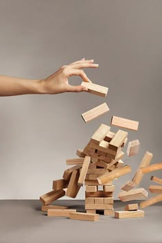 a pile of wooden blocks being tossed by a person's hand over the top