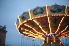 a merry go round ride with lights on it's sides in the evening time