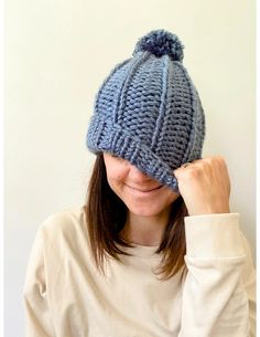 a woman wearing a blue knitted hat with a pom - pom on it