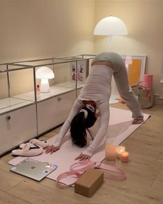 a woman is doing yoga on the floor in front of a laptop and other items