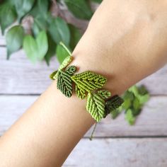 a woman's arm with a green leaf bracelet on it