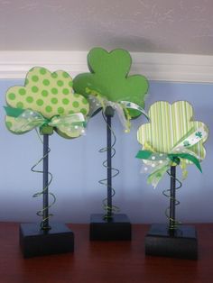 four black vases with green and white flowers in them sitting on a wooden table