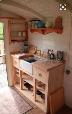 a kitchen area with sink, stove and shelves on the wall next to an open door