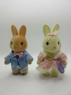 two stuffed animals dressed in clothes on a white background