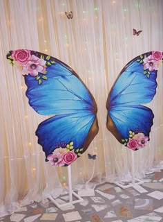 two blue butterflies with pink flowers on their wings are standing in front of a curtain