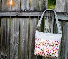 a purse hanging on a wooden fence next to a red and white flowered bag