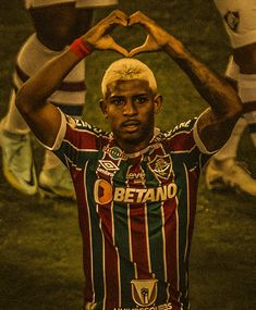 a man making a heart shape with his hands while standing in front of soccer players