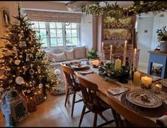 a dining room table set for christmas with candles and decorations on the tables in front of it