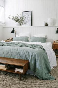 a bed sitting in a bedroom next to a wooden dresser and lamp on top of a table