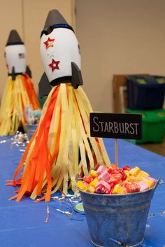 a blue table topped with lots of candy next to a bucket of candies and a sign that says starburst