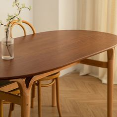 a wooden table with chairs around it and a vase on the table next to it