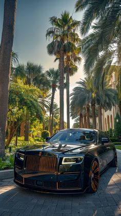 a black rolls royce parked on the side of a road next to some palm trees