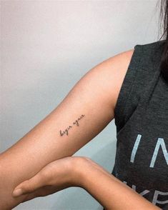 a woman with a small tattoo on her arm and the word love is written in cursive writing