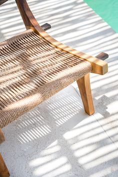 a wooden bench sitting on top of a cement floor next to a swimming pool in the sun