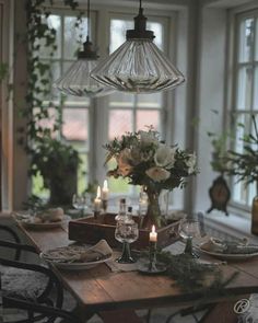 a dining room table is set with candles and flowers in vases on the table