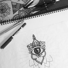 an eye drawn on paper next to pens and scissors