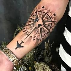 a man with a compass tattoo on his arm and wrist is holding an airplane in front of him