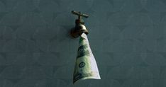 a roll of money hanging from a faucet