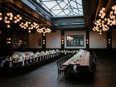 an empty banquet hall with tables and chandeliers hanging from the ceiling, filled with white flowers