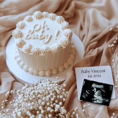 there is a baby announcement next to a cake on top of a table with flowers