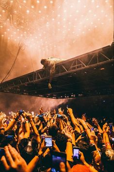 a man standing on top of a stage surrounded by people holding up their cell phones