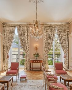 a living room filled with furniture and a chandelier hanging from the ceiling next to two windows