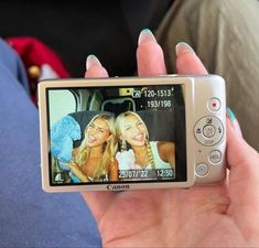 a person holding up a cell phone with two girls on it