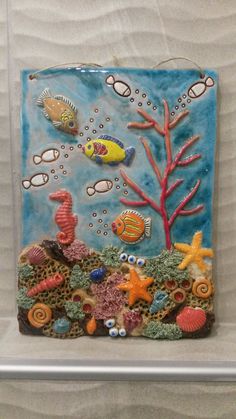 a ceramic tile with sea animals and corals on the bottom is displayed in a glass case