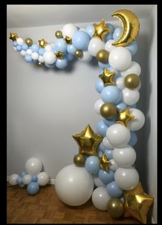 a balloon arch with stars and moon balloons on the top is decorated in blue, white and gold colors