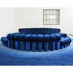 a blue circular couch sitting in the middle of a room