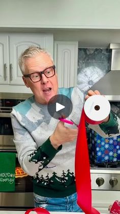 an old man is making christmas decorations in the kitchen with scissors and tape on his head