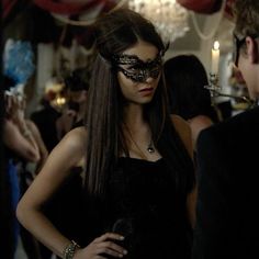 a woman in a masquerade standing next to a man wearing a black mask