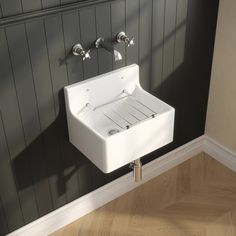 a white sink sitting on top of a wooden floor next to two faucets