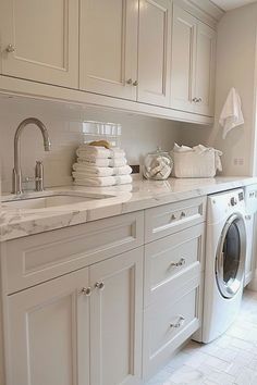 a washer and dryer in a white kitchen with marble counter tops on the counters