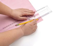 a child's hand holding a pencil and measuring the height of a piece of paper