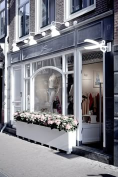 a storefront with flowers in the window and mannequin's head on display